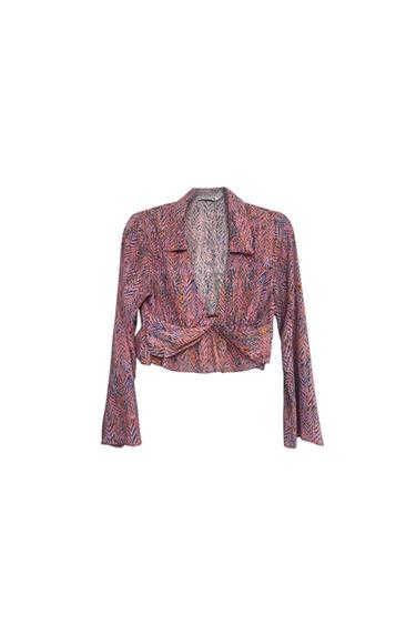 Front view of a multicoloured printed blouse with a knot at the front and long sleeves.