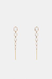 Dlouh� zlat� n�u�nice s kruhov�mi prvky a osazen�mi drahokamy, zap�n�n� na puzetu.