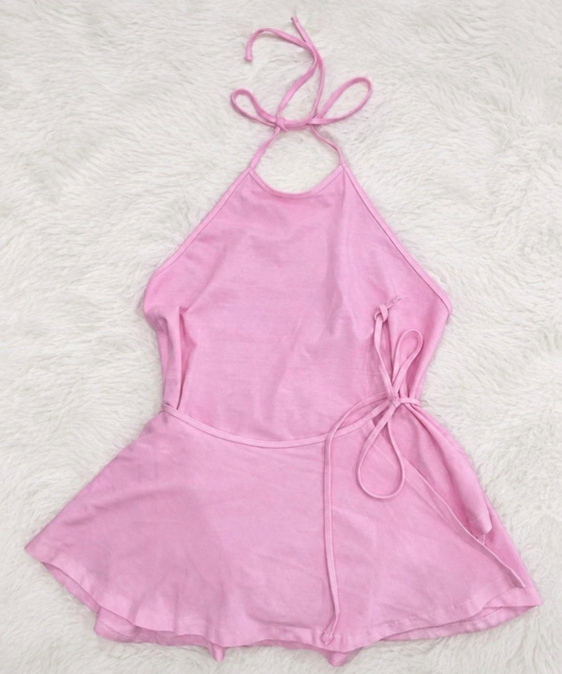 Pink halterneck top with ties at the neck and waist, and a flared hem, set against a fluffy white background.