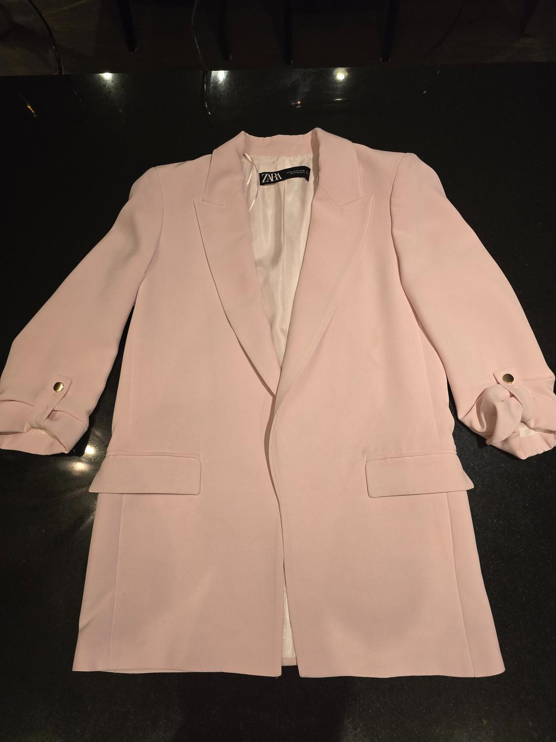 Light pink long-sleeved jacket with lapels and pockets, on a dark background. Visible tag: ZARA.