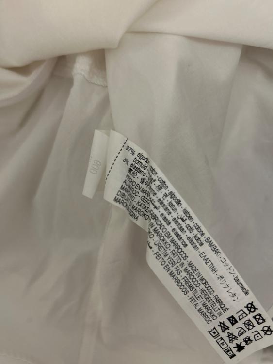 White clothing label with care instructions and composition: 97% cotton, 3% elastane. Made in Morocco. Visible washing symbols.