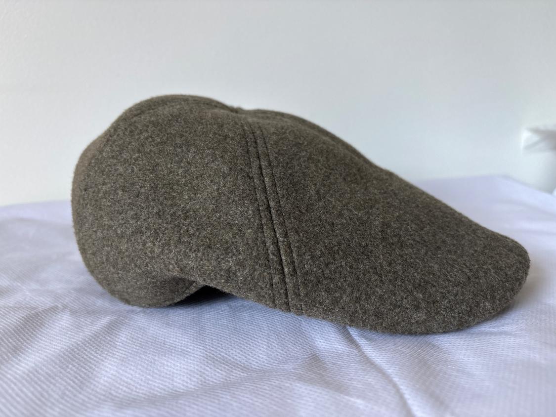 Grey woolly hat on a white surface, with visible seams and classic design. White background and minimalist atmosphere.