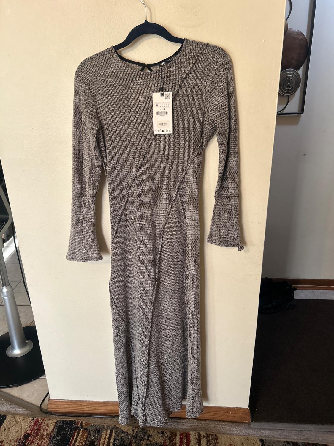Textured grey maxi dress with long sleeves, hanging on a black hanger. Visible label with price and size M details.