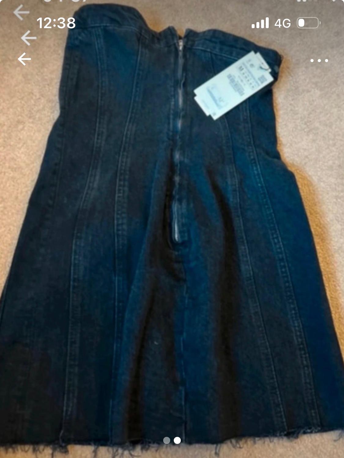 Dark blue denim dress with a rear zip and visible label, on a beige carpet background.