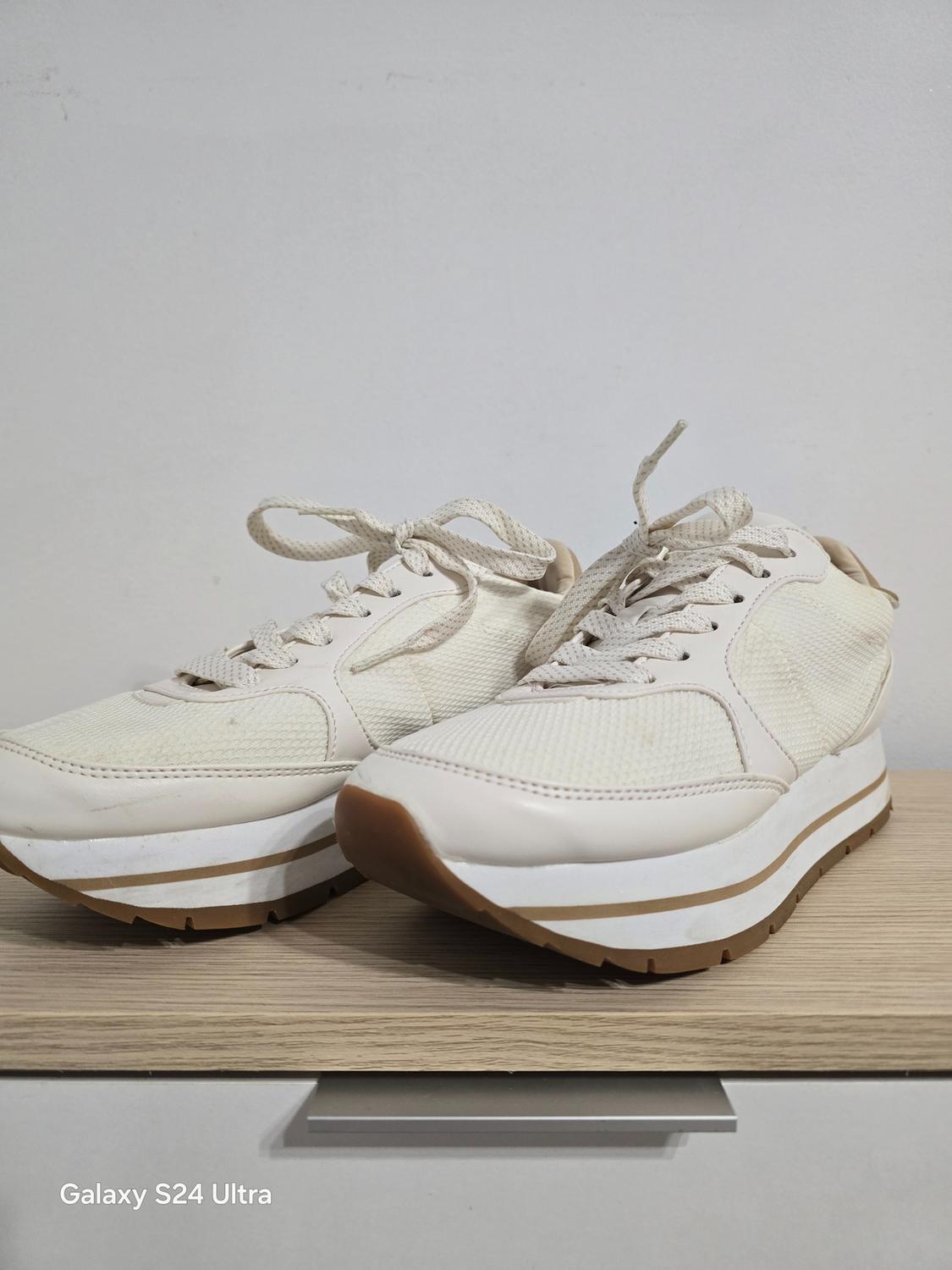 Side view of white trainers with a thick sole and laces.
