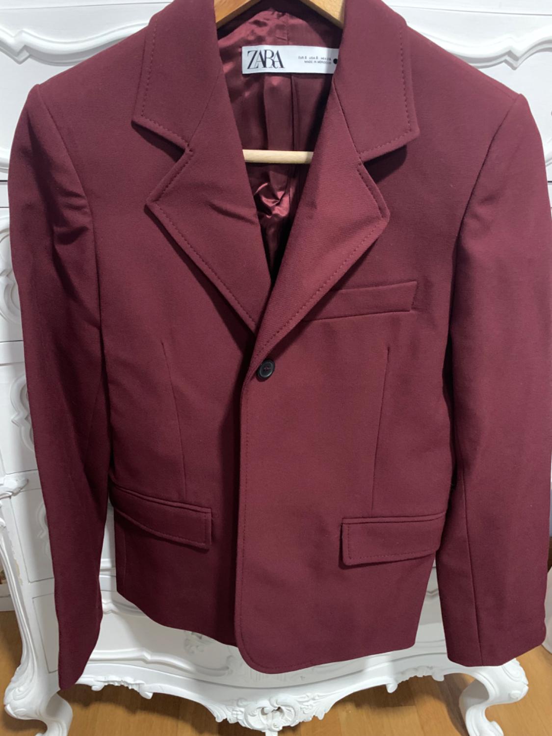 Front view of a burgundy jacket with lapels, a one-button fastening, and flap pockets.