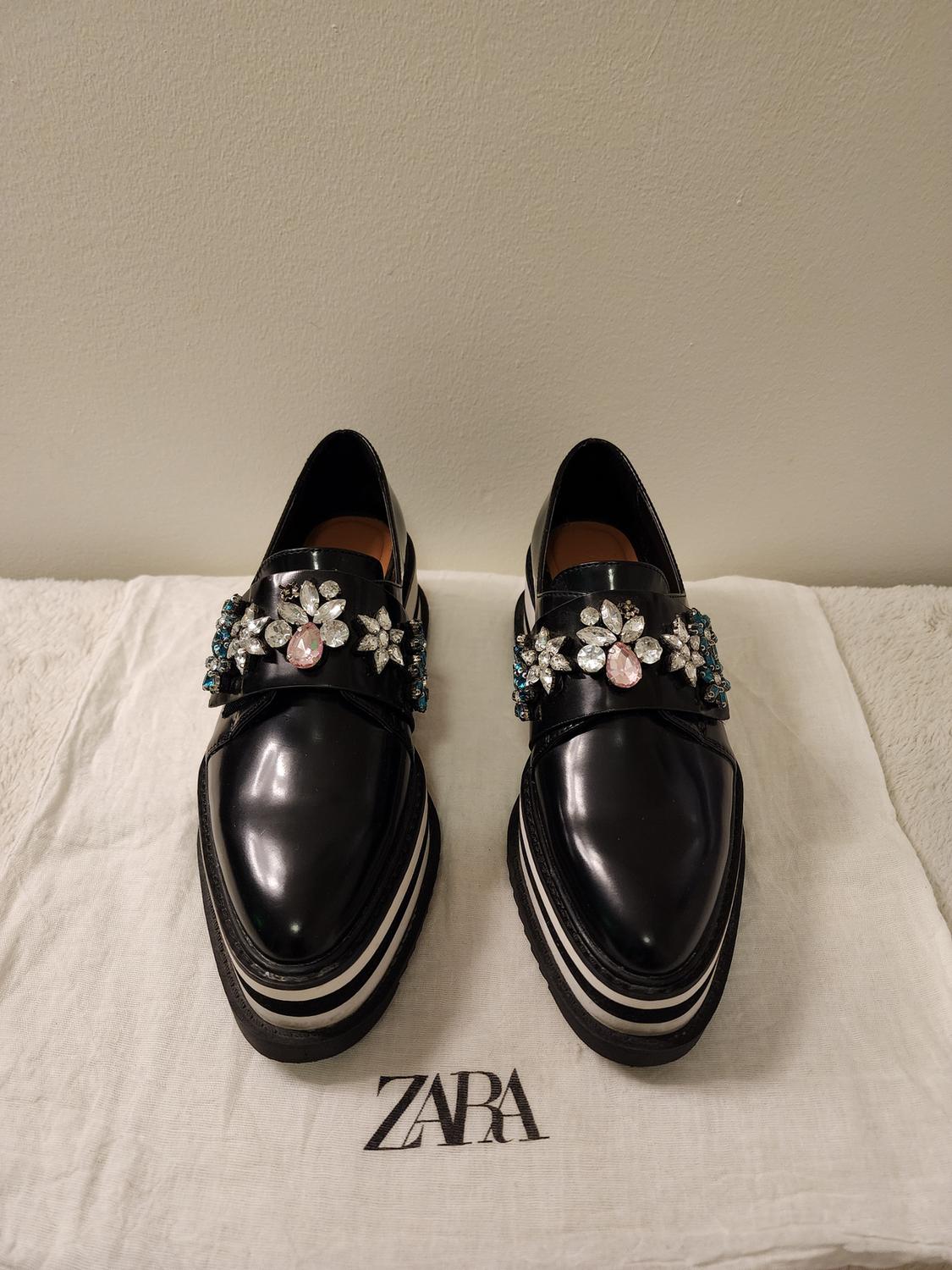 Front view of black loafers with rhinestones on fabric with 'ZARA' text.