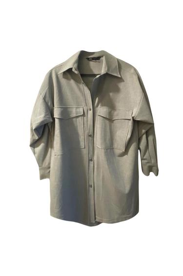 Front view of a gray shirt with buttoned flap front pockets.