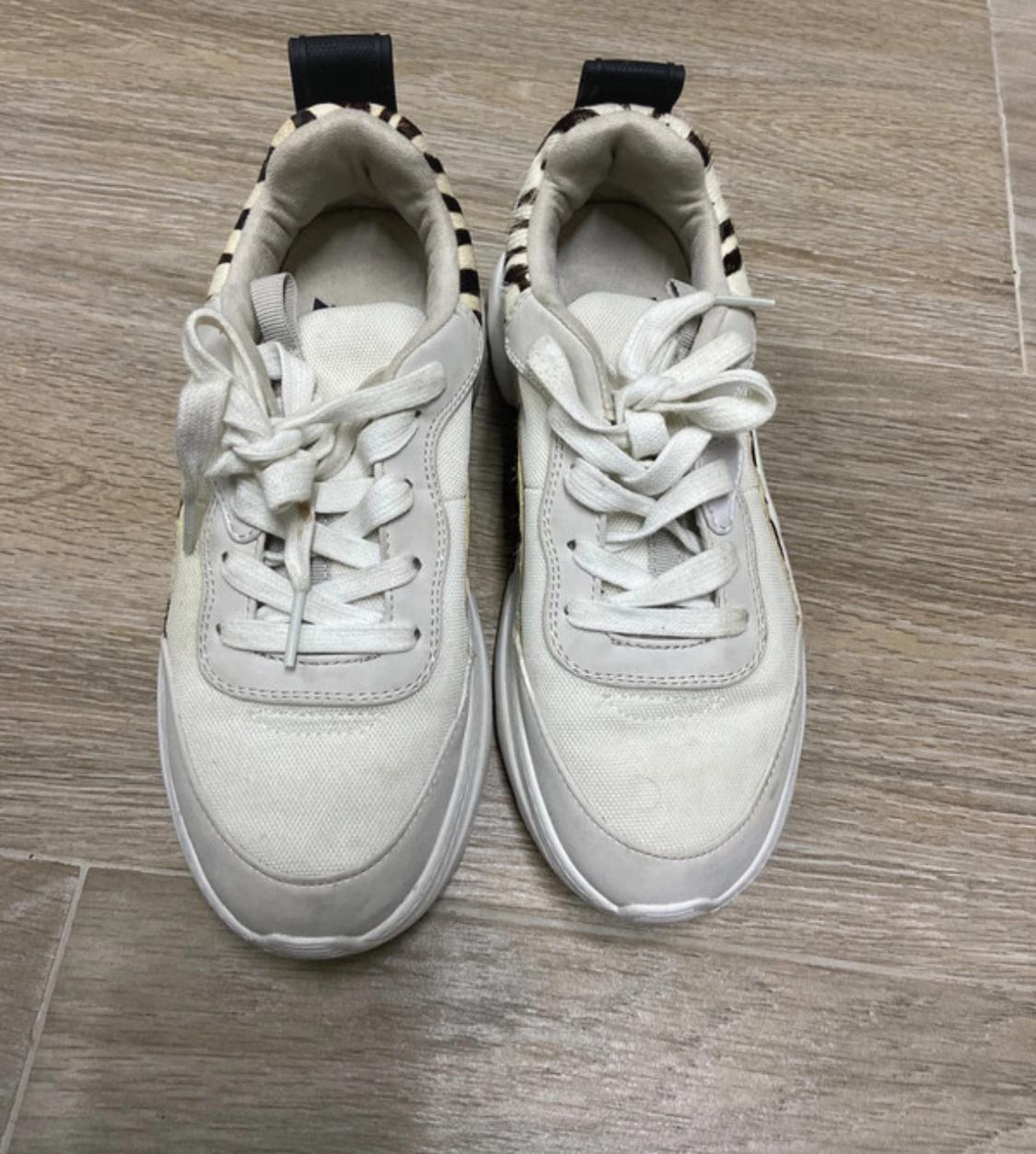 Front view of white trainers with laces and animal print detailing on the heel.