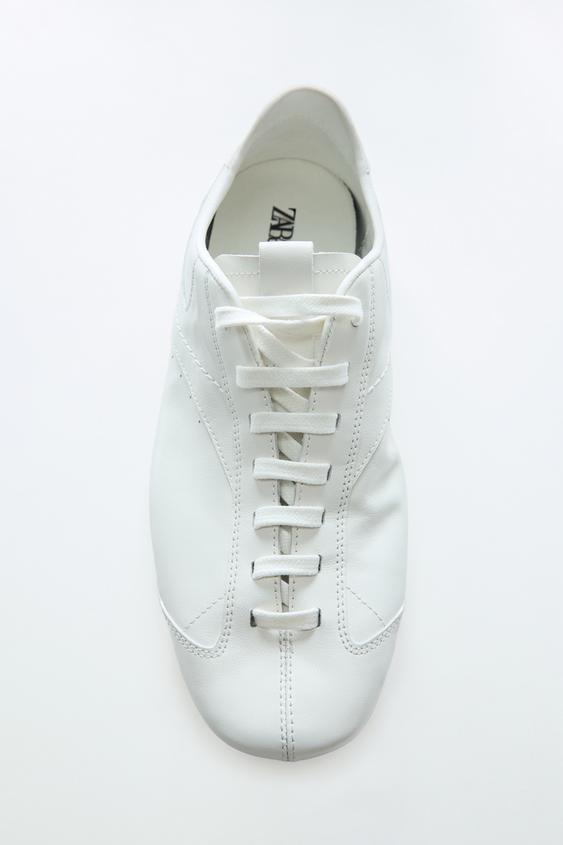 Pohled shora na b�lou sportovn� botu typu blucher se �n�rov�n�m a viditeln�m pro��v�n�m. Vnit�n� text: "ZARA".