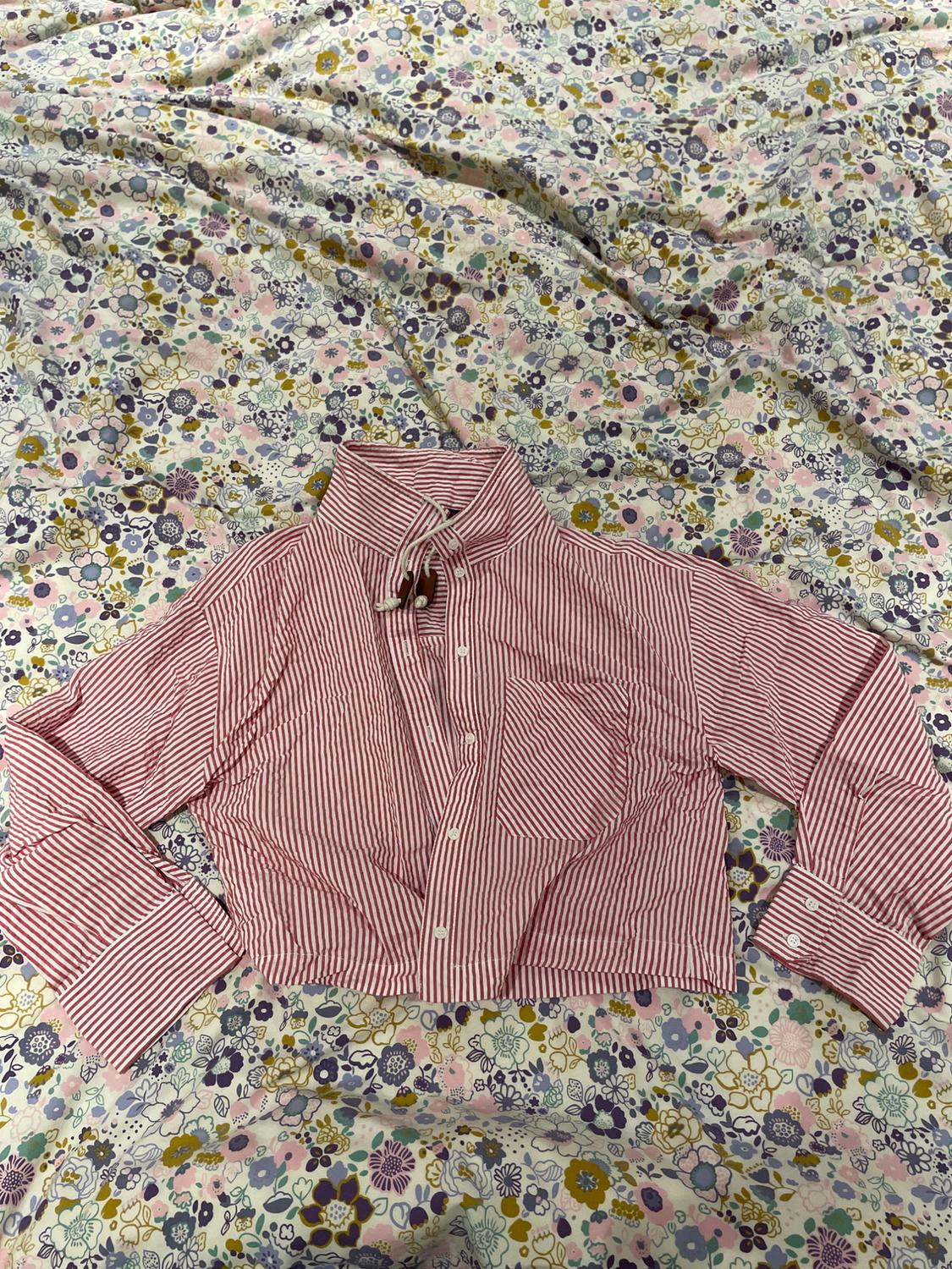 Red and white striped shirt with a high neck and front pocket, over floral fabric in pastel shades.