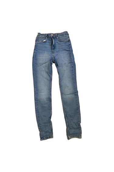 Distressed blue denim jeans on a white background, featuring a button and zip fastening, five pockets and a straight leg.