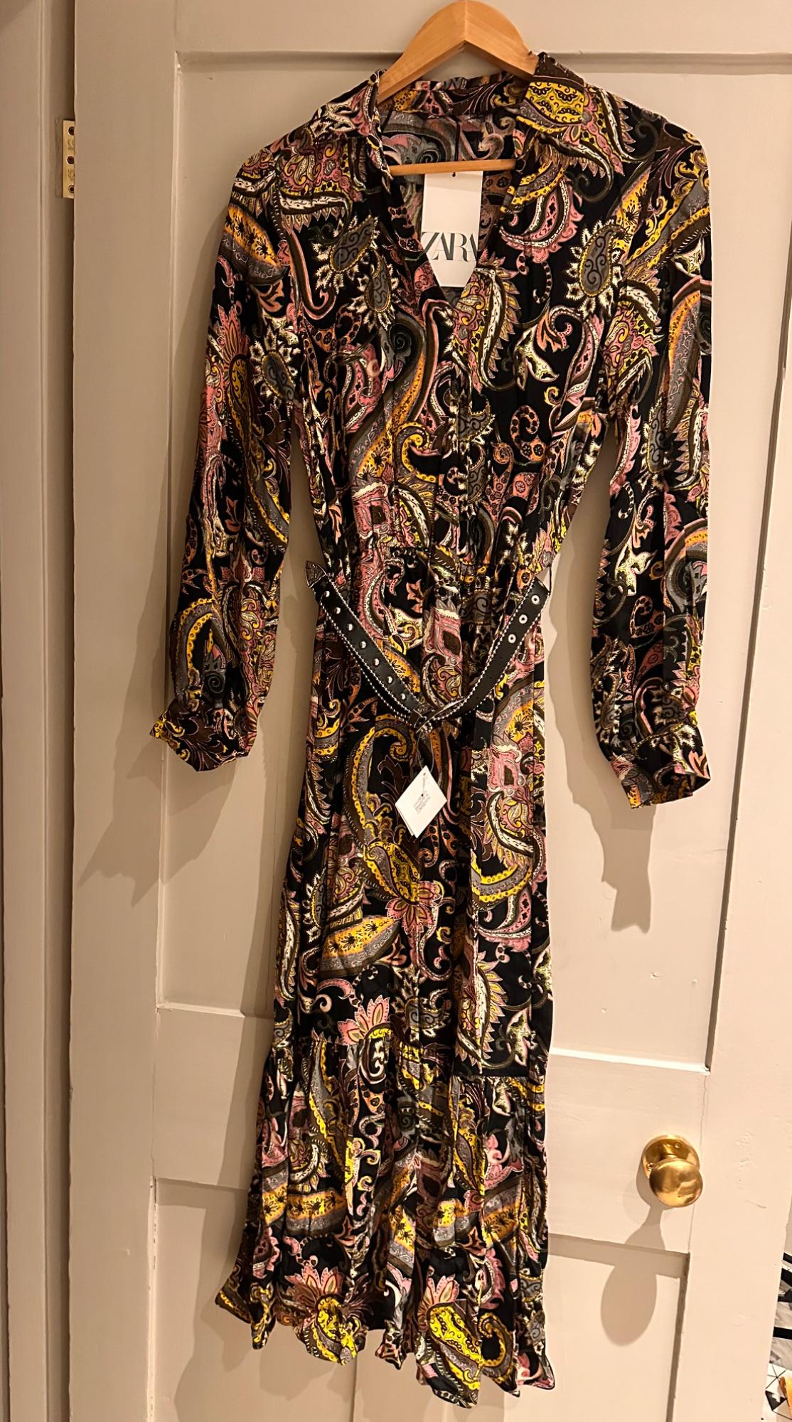 Dress hanging with paisley print in shades of black, yellow and pink. Visible label with the text "ZARA".