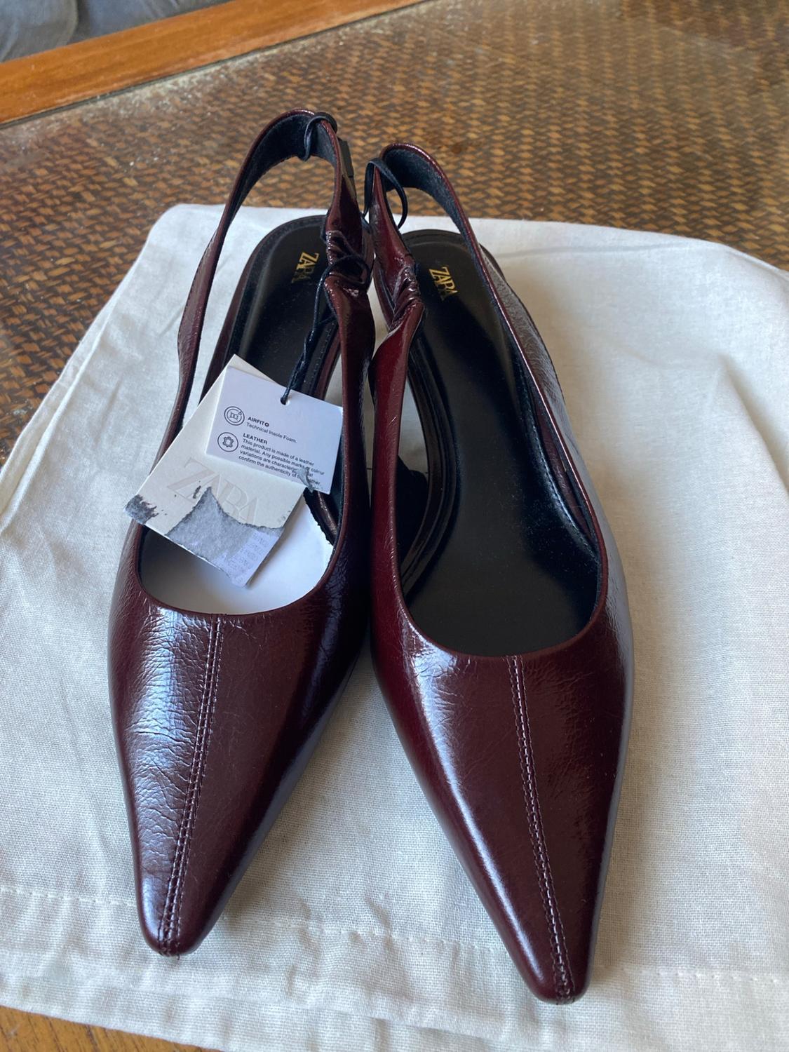 Γυαλιστερά μπορντό slingback παπούτσια με μυτερή μύτη σε λευκό ύφασμα.
Περιλαμβάνει ετικέτα με το κείμενο ZARA AIRFIT LEATHER.