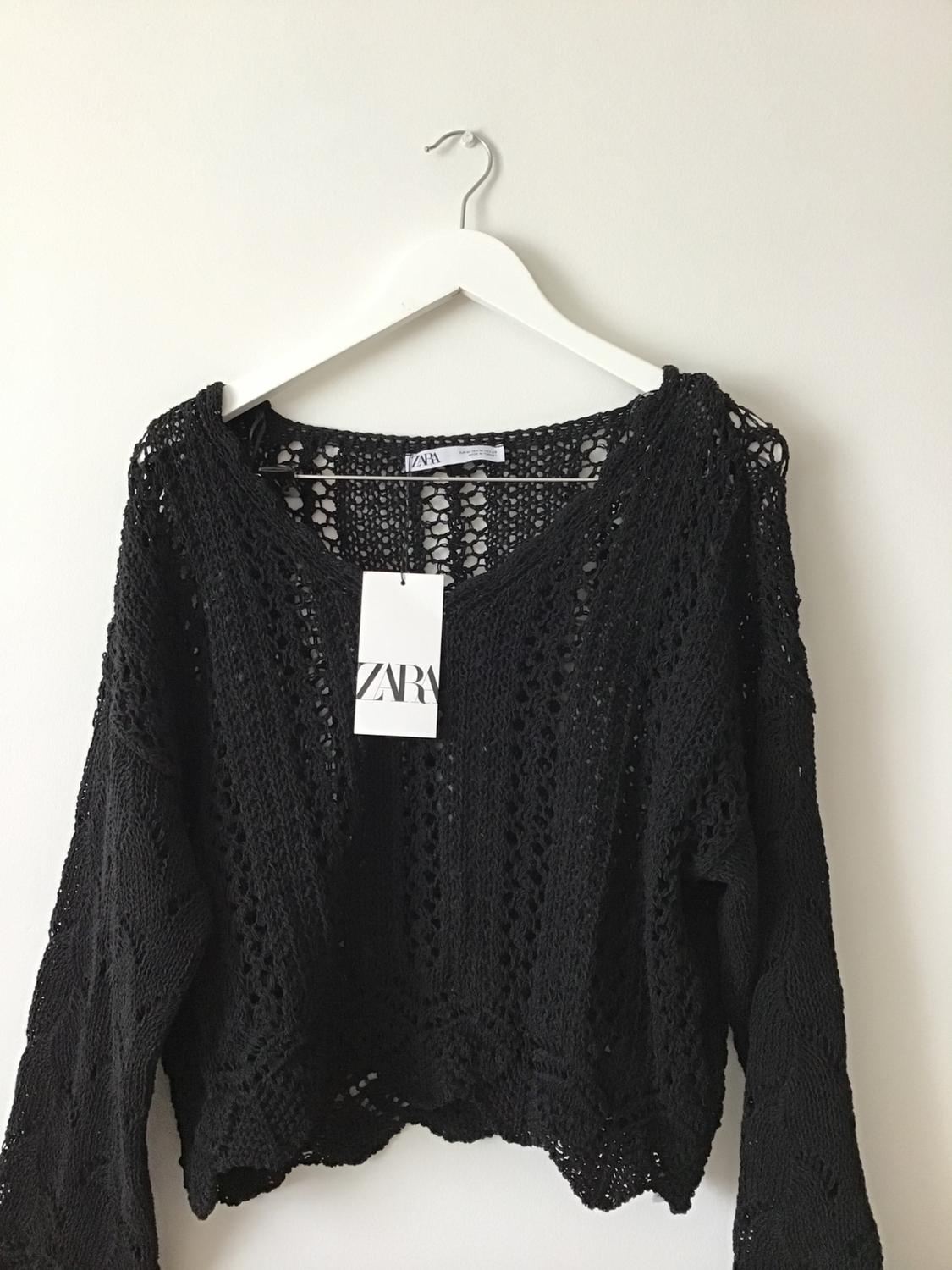 Front view of a black chunky knit jumper with a visible label that says 'ZARA'.