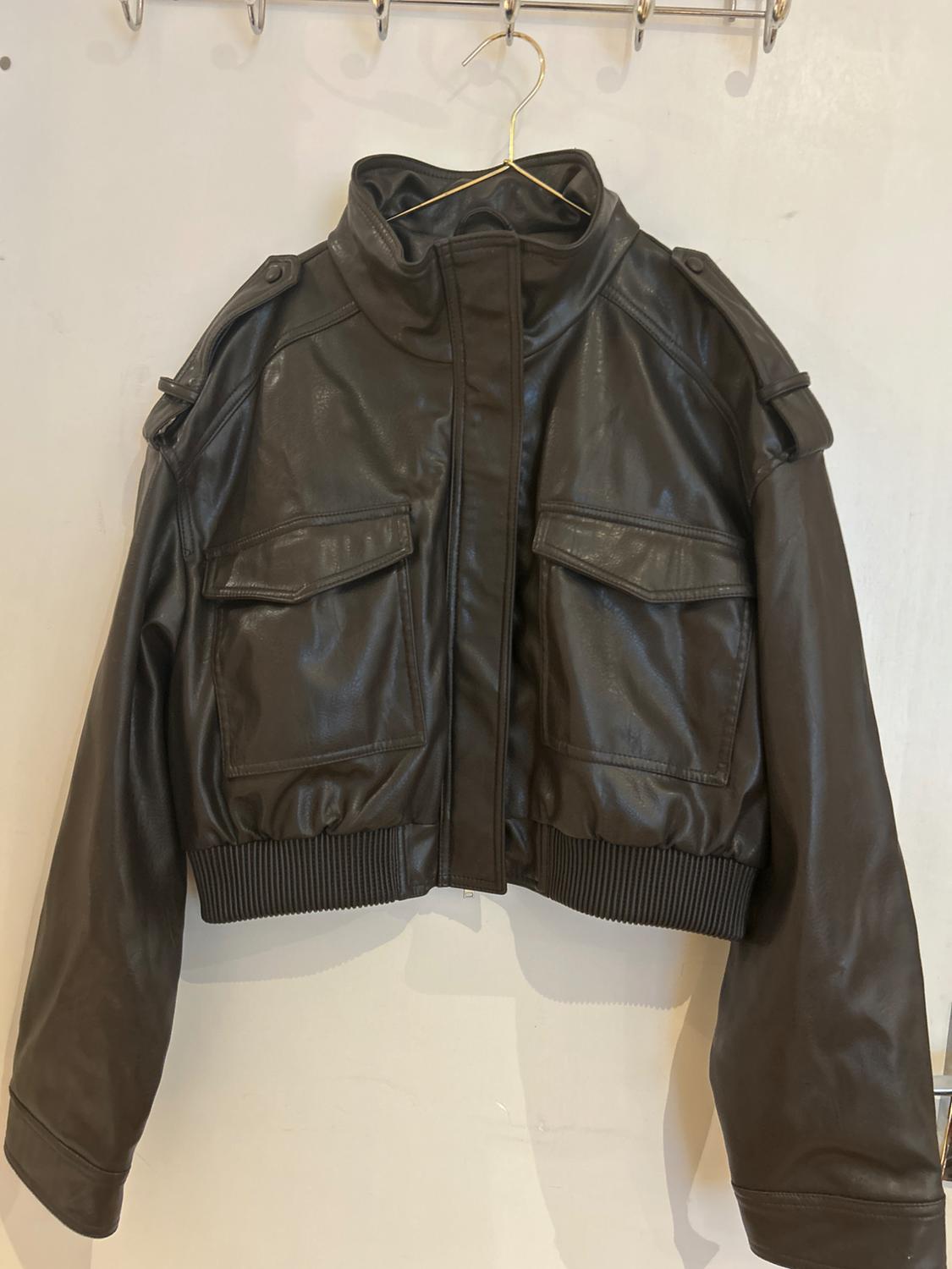 Dark brown bomber jacket with a high collar, flap pockets and an elasticated hem, hanging on a hanger against a white background.