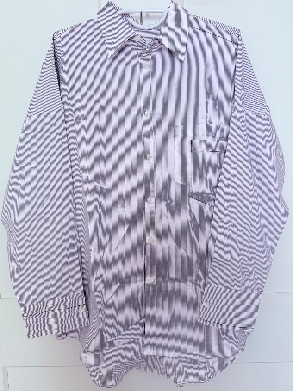 Fine white and blue striped shirt hanging on a hanger, with front buttons and a chest pocket.