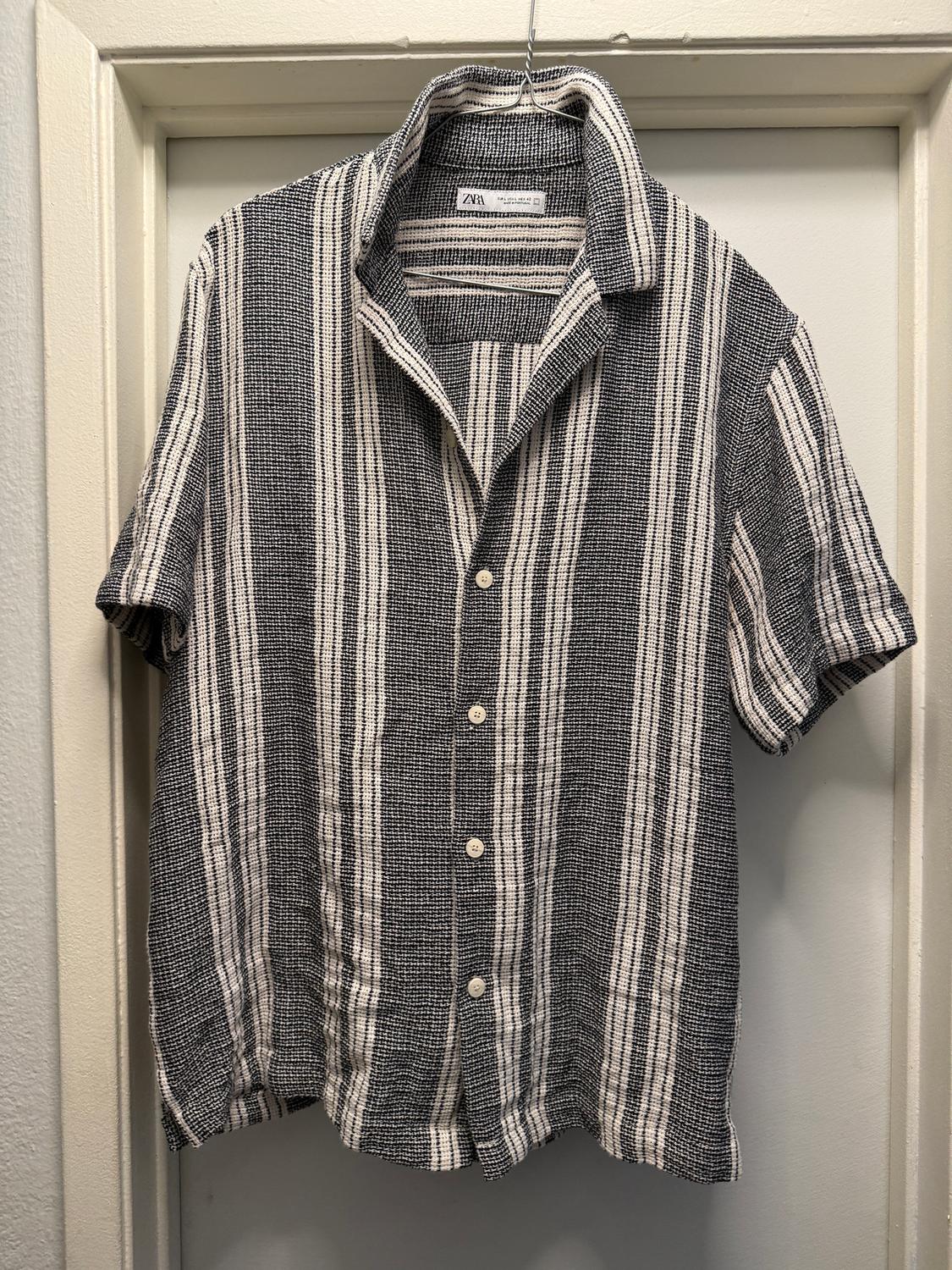 Black and white vertical striped shirt hanging on a hanger. Visible tag with the text "Zara".