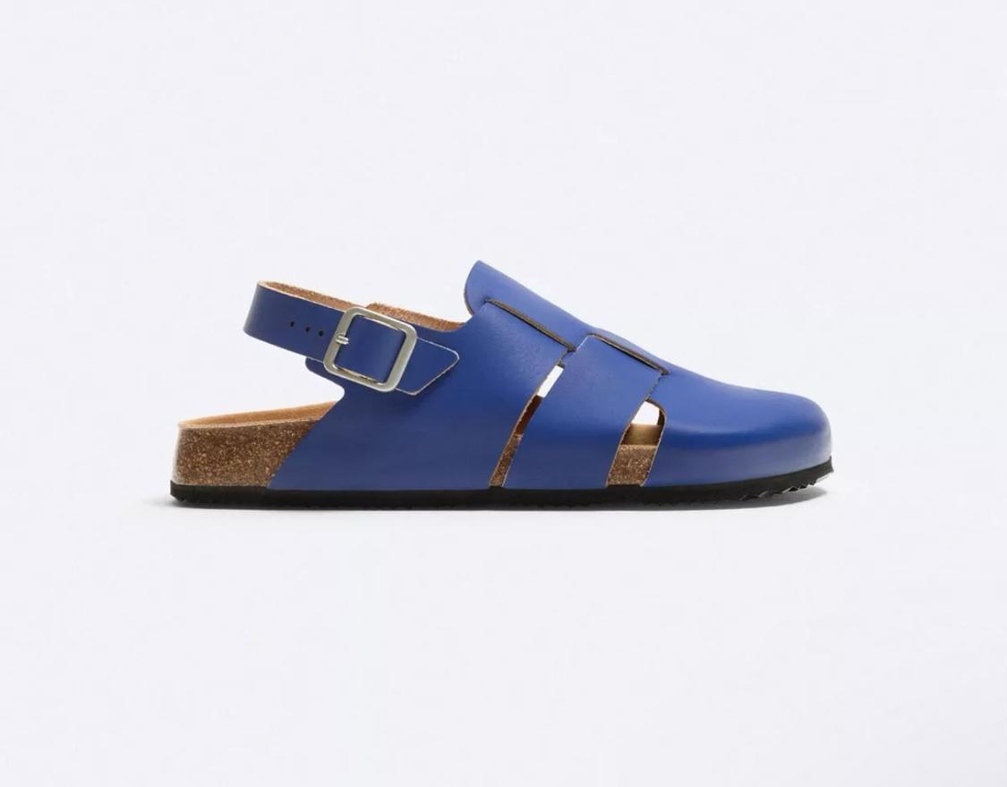 Side view of a blue sandal with a buckle and cork sole.
