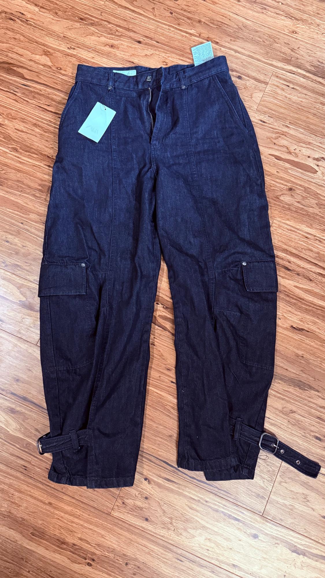 Dark blue cargo jeans on a wooden floor. Includes side pockets, buckled straps at the hem, and a ZARA label.