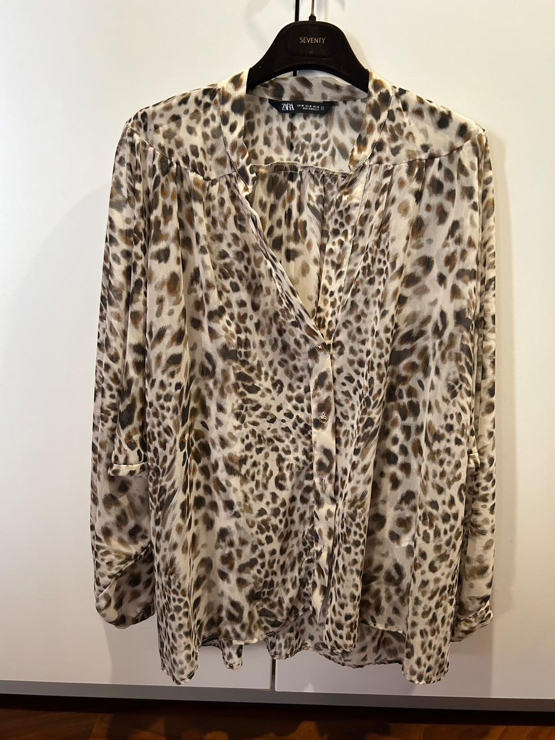 Μπλούζα με animal print σε καφέ και μπεζ αποχρώσεις, κρεμασμένη σε μια μαύρη κρεμάστρα με το λογότυπο "SEVENTY" εμφανές.