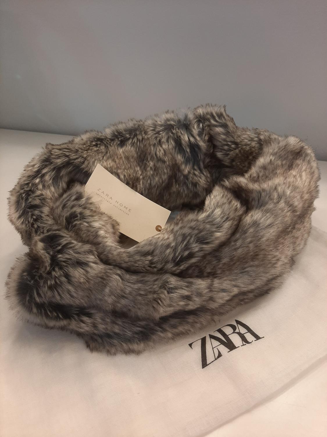 Close-up of grey fur scarf on white bag with 'ZARA' text.