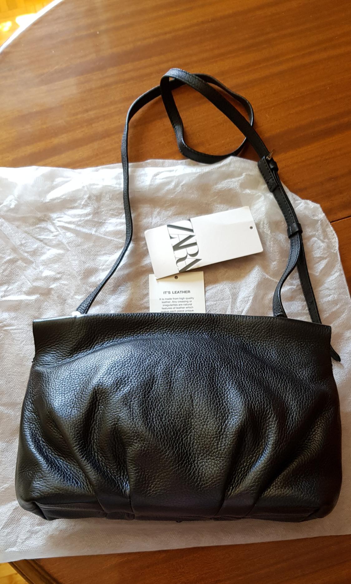 Black bag with adjustable strap and visible tag.