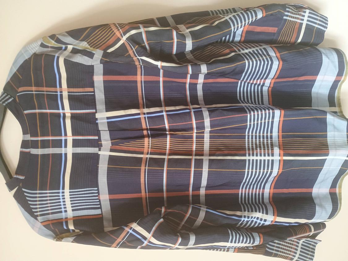 Long-sleeved checked shirt in shades of blue, white, and orange, hanging on a hanger against a white background.