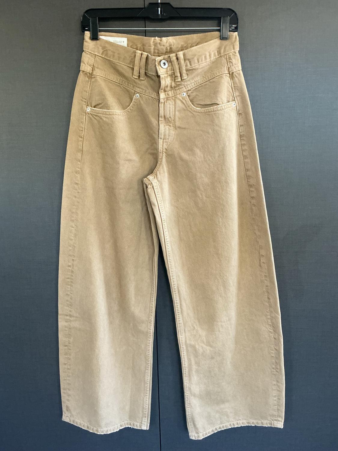 Wide beige denim-style pants hanging on a black hanger against a dark gray background. Casual design with five pockets.
