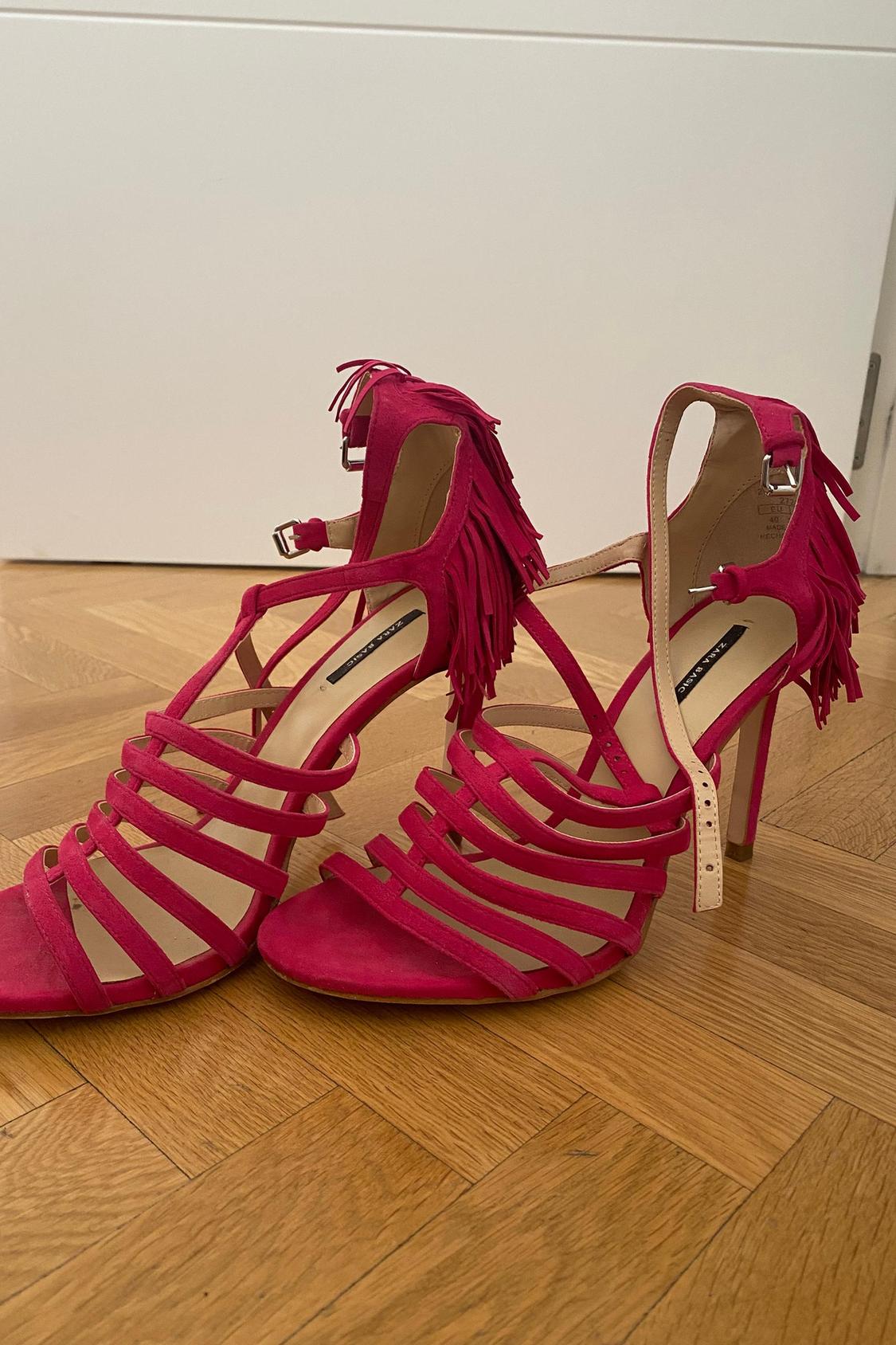 Front view of pink high-heeled sandals with fringes and crossed straps.
