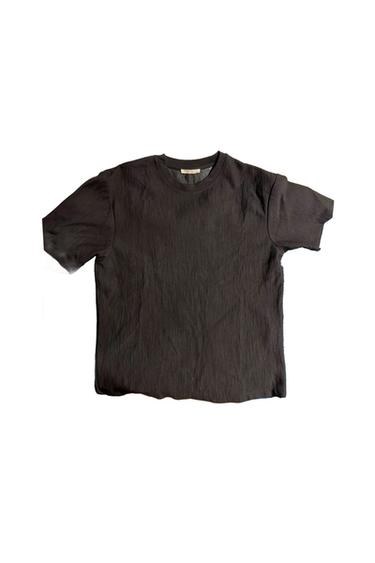 Black short-sleeved t-shirt with textured fabric on a white background.