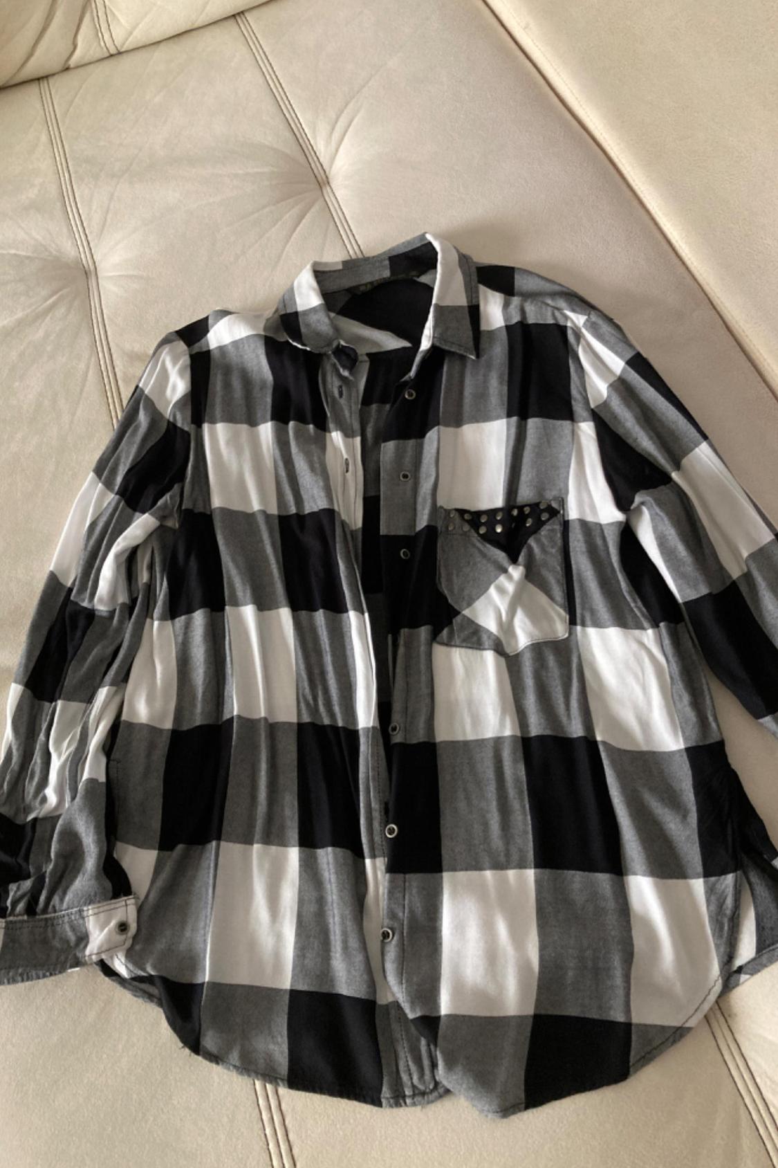 Front view of a black and white checked shirt with a pocket decorated with studs.