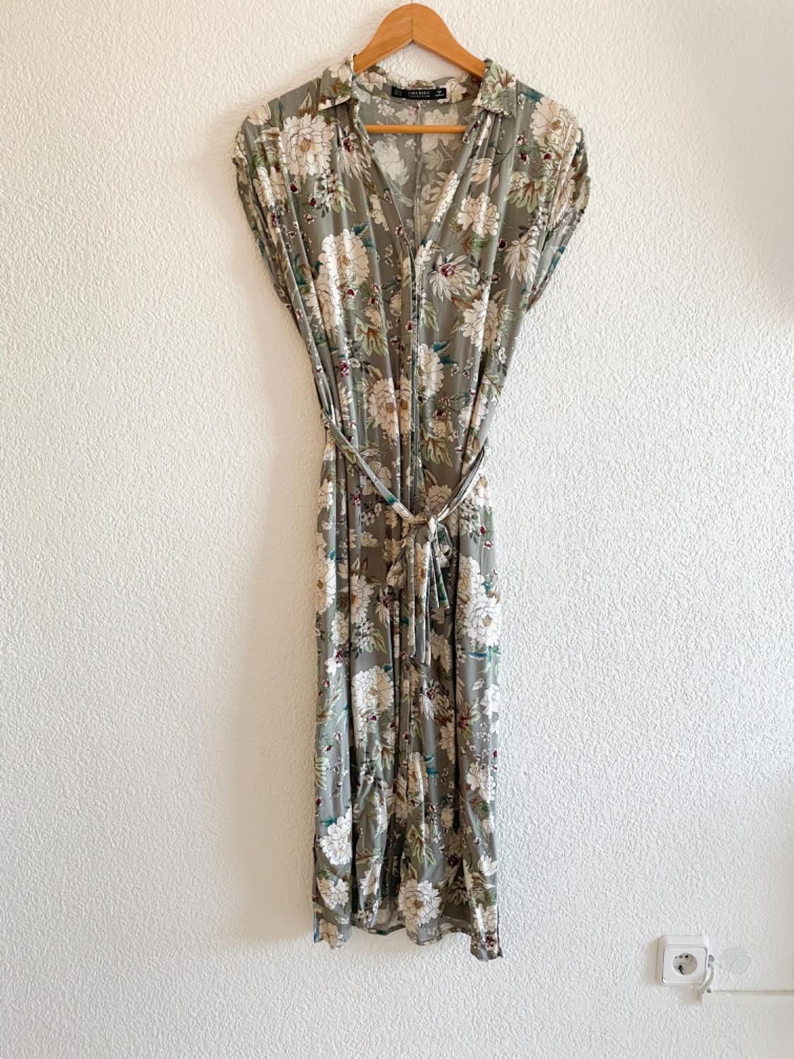 Front view of a long dress with a green and white floral print, featuring an adjustable belt.