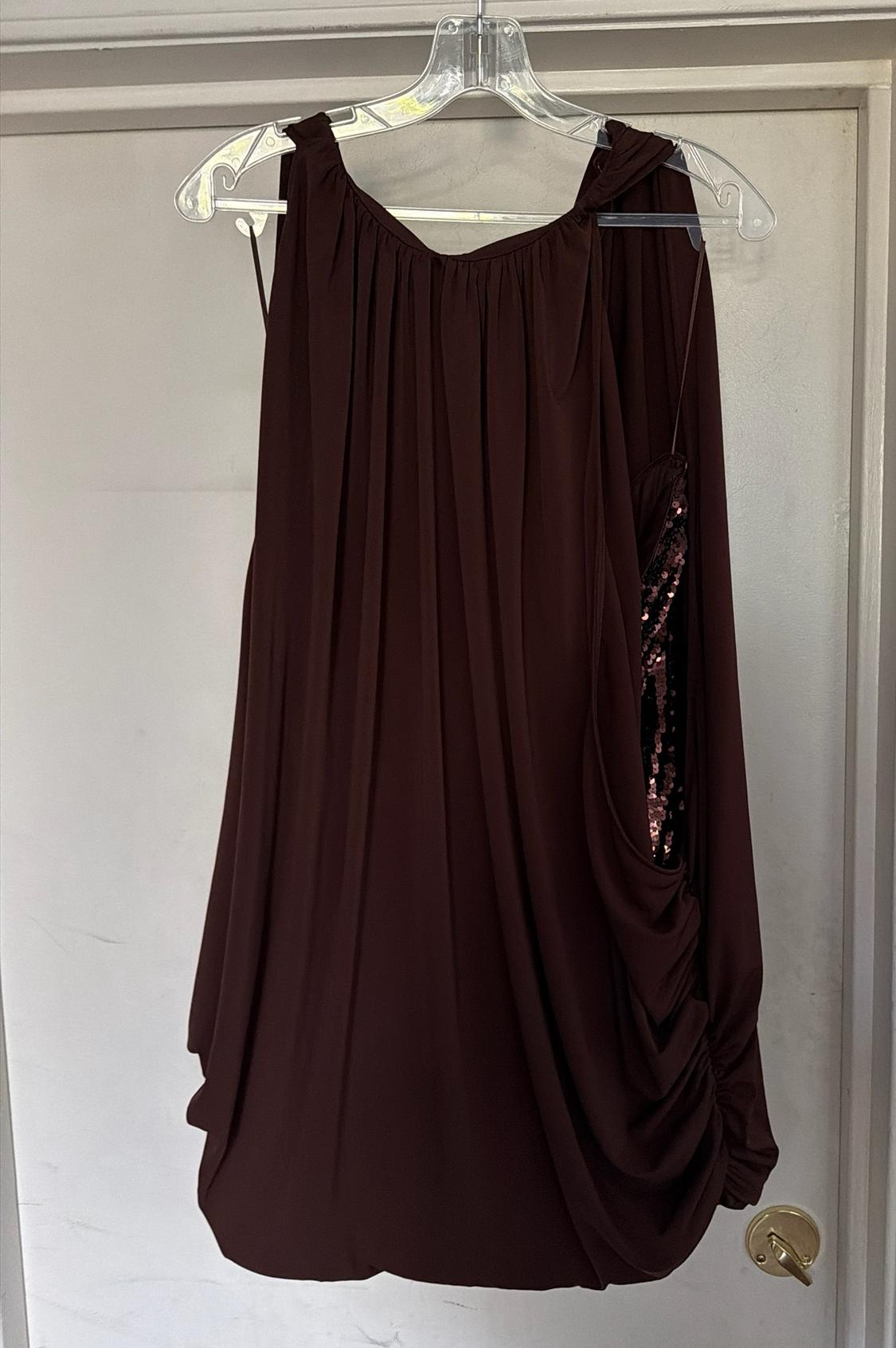 Dark brown draped dress on a hanger over a white door. It features a side detail that reveals shimmering sequins.
