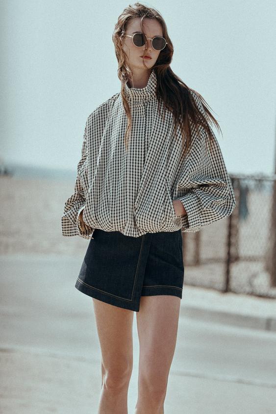 Souprava černo-krémové kostkované bomber bundy s rolákem a dlouhými rukávy a černé krátké sukně.