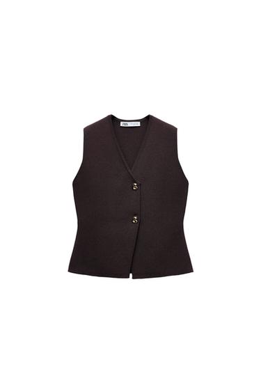 Dark brown knitted waistcoat with a V-neck, asymmetric fastening and two gold-coloured buttons on a white background. Label with ZARA text.
