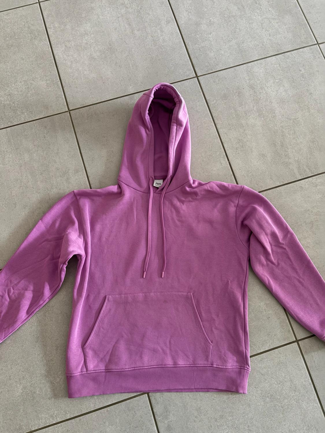 Purple hooded sweatshirt with drawstrings and a front pocket. ZARA label at the neck. Laid out on a grey tiled floor.