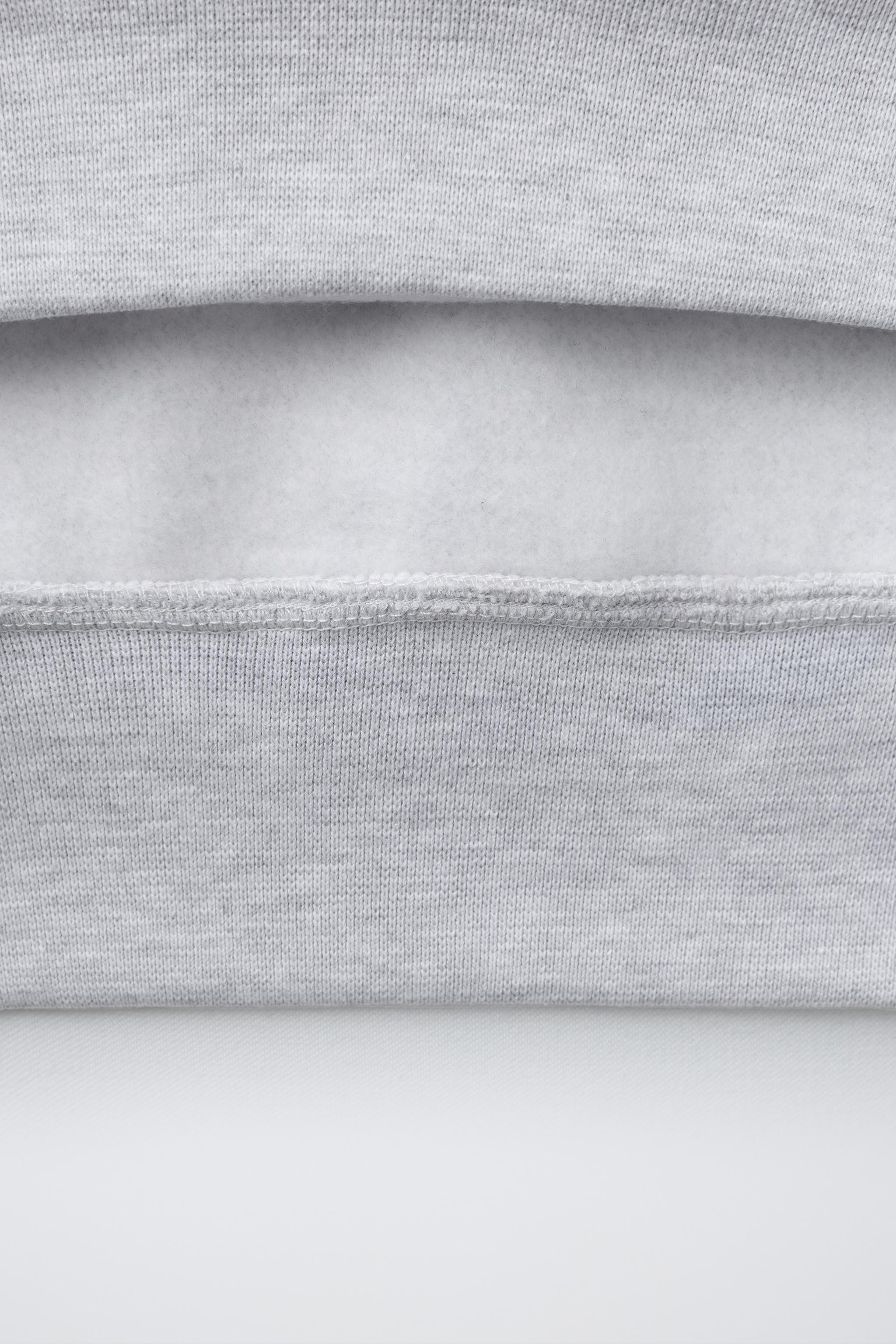 SWEAT À CAPUCHE ET INSCRIPTION