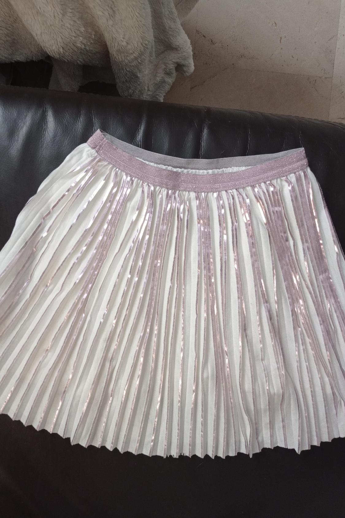 Front view of a white pleated skirt with sparkly details and a pink elastic waistband.