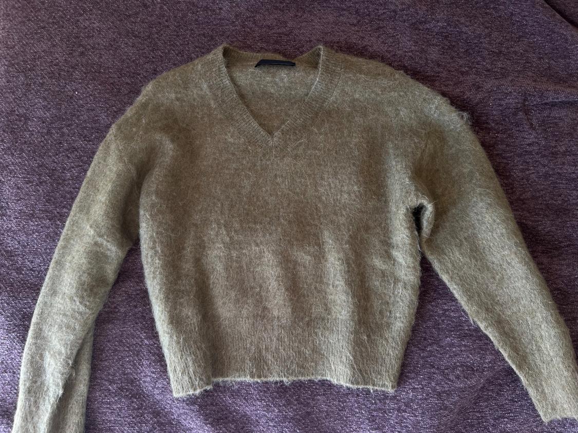 Brown V-neck long-sleeved wool jumper, placed on a purple textile surface.