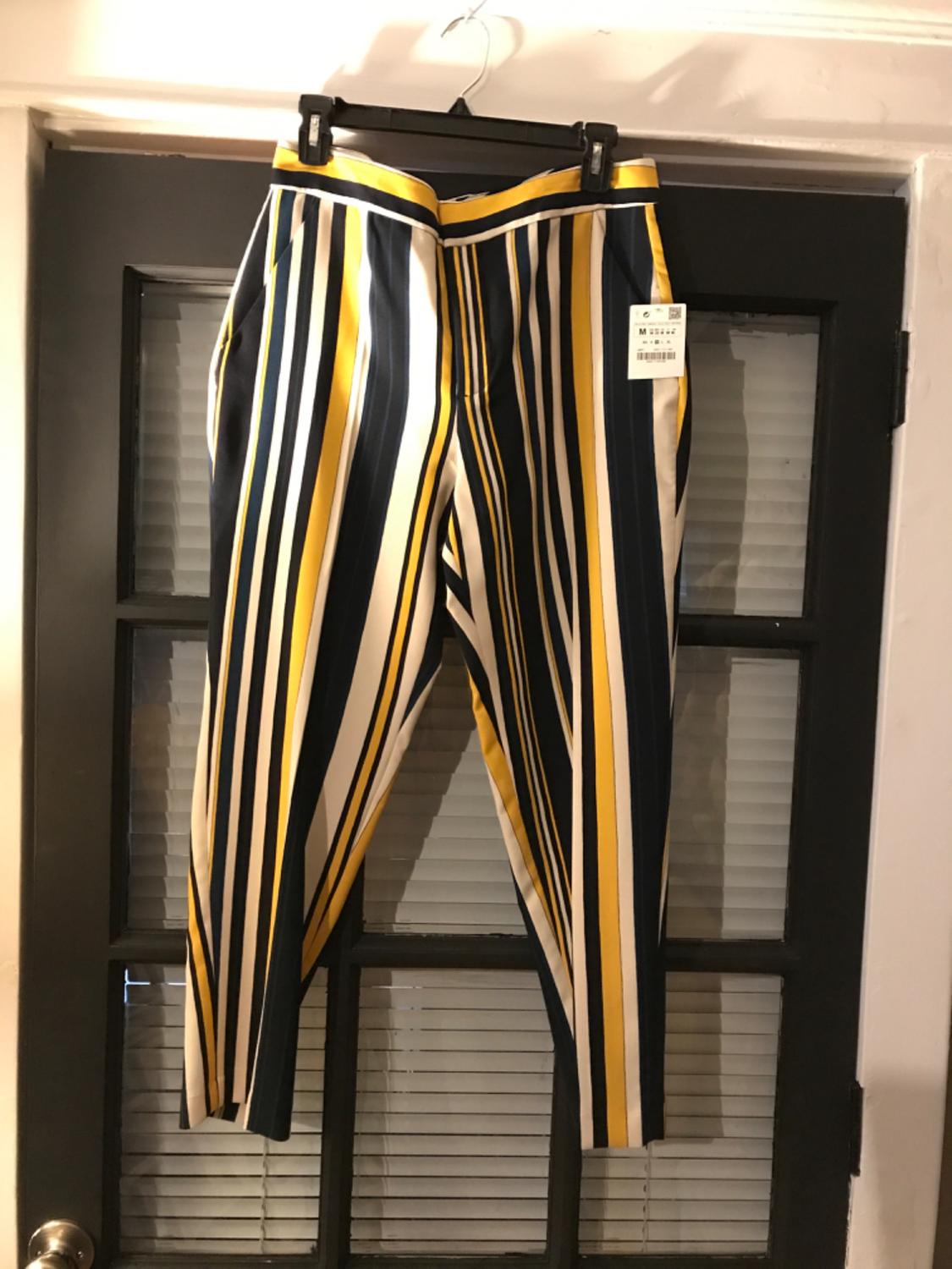 Front view of vertical striped trousers in yellow, white, and navy blue, with side pockets.