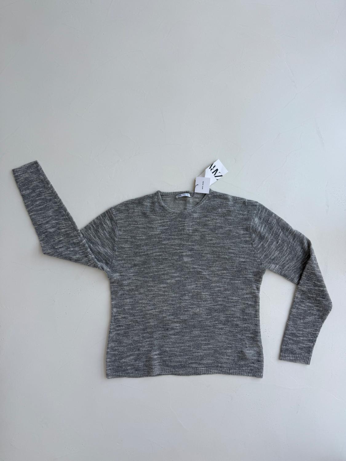 Grey long-sleeved jumper on a white background, with a visible label at the neck.