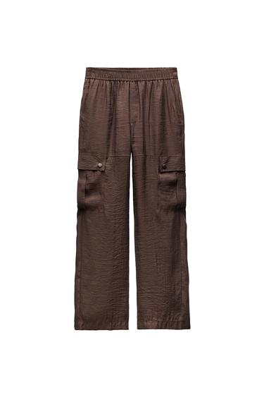 Front view of brown trousers with side pockets with flap and button fastening.