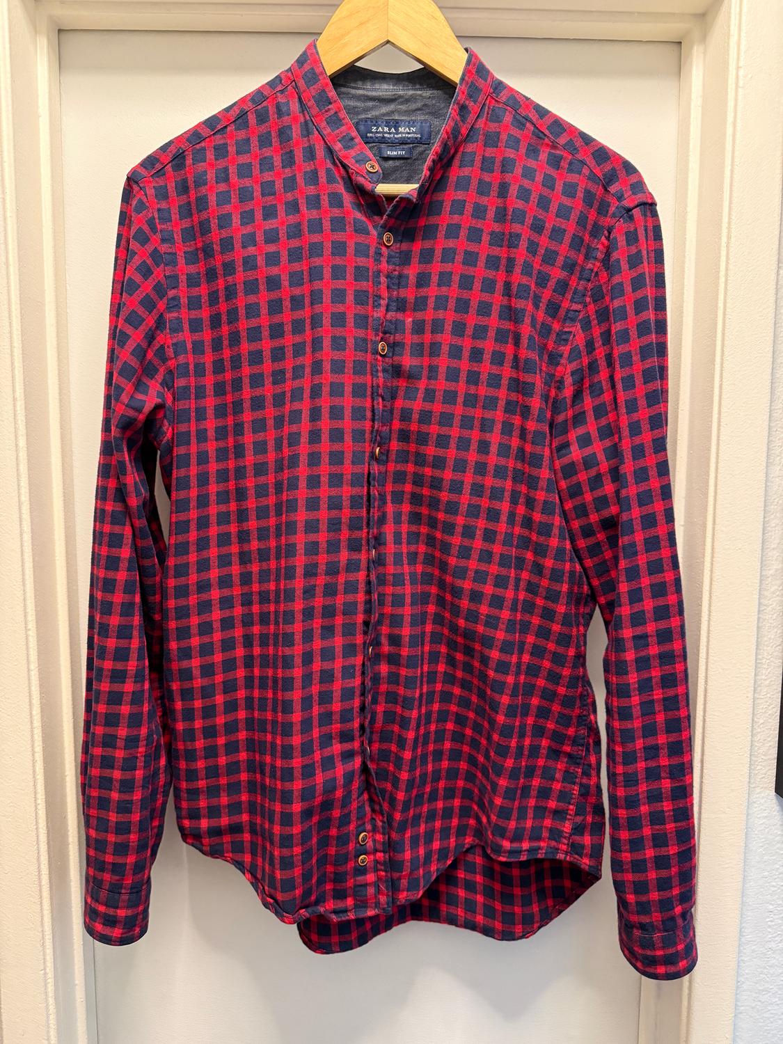Red and blue plaid shirt hanging on a wooden hanger. Visible tag: "ZARA MAN". White background.