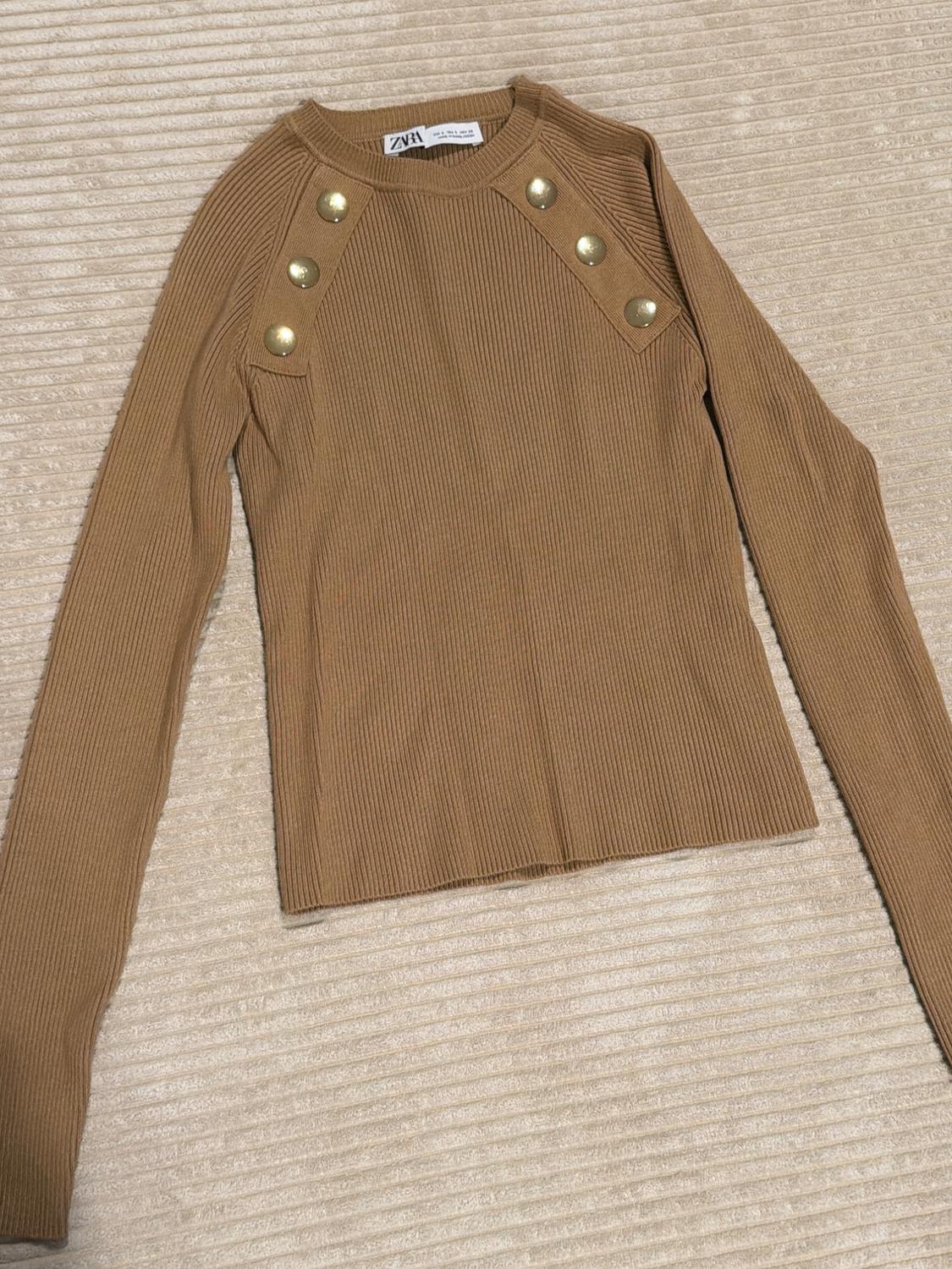 Camel rib-knit long-sleeve sweater with a crew neck and gold buttons on the shoulders. ZARA label visible inside.