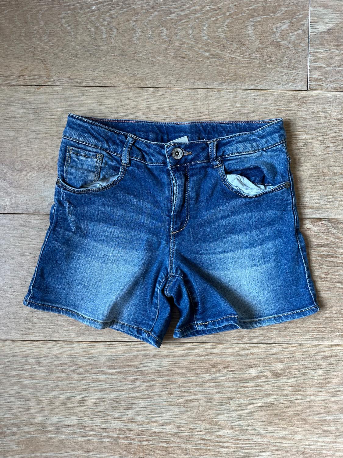 Front view of blue denim shorts with front pockets and visible button.