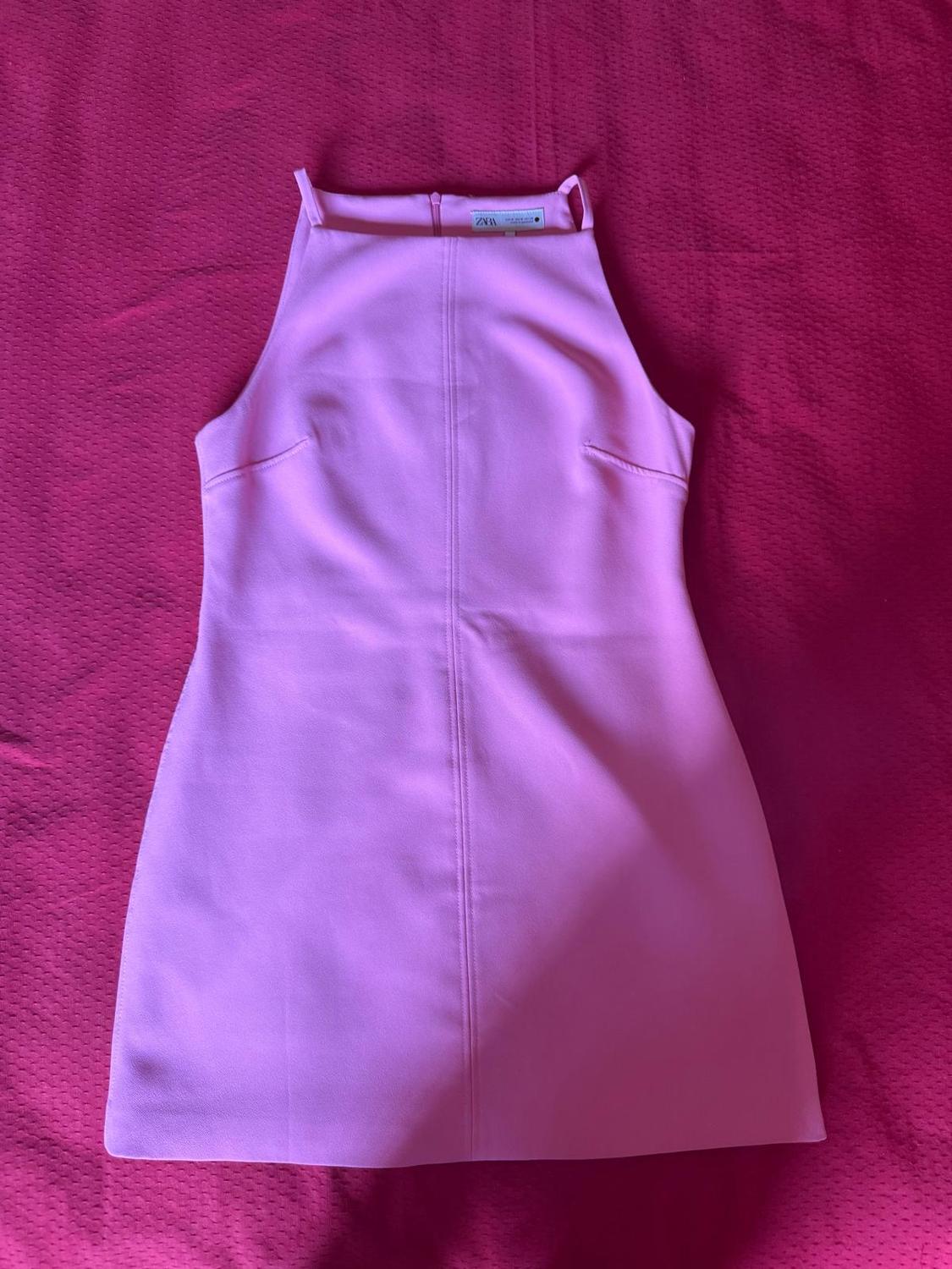 Short, light pink, sleeveless dress against a dark pink fabric background. The inside label reads ZARA.