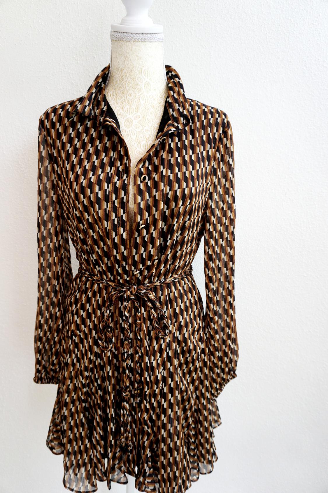 Long-sleeved dress with a geometric print in brown and beige tones, cinched at the waist with a tie, displayed on a white mannequin.