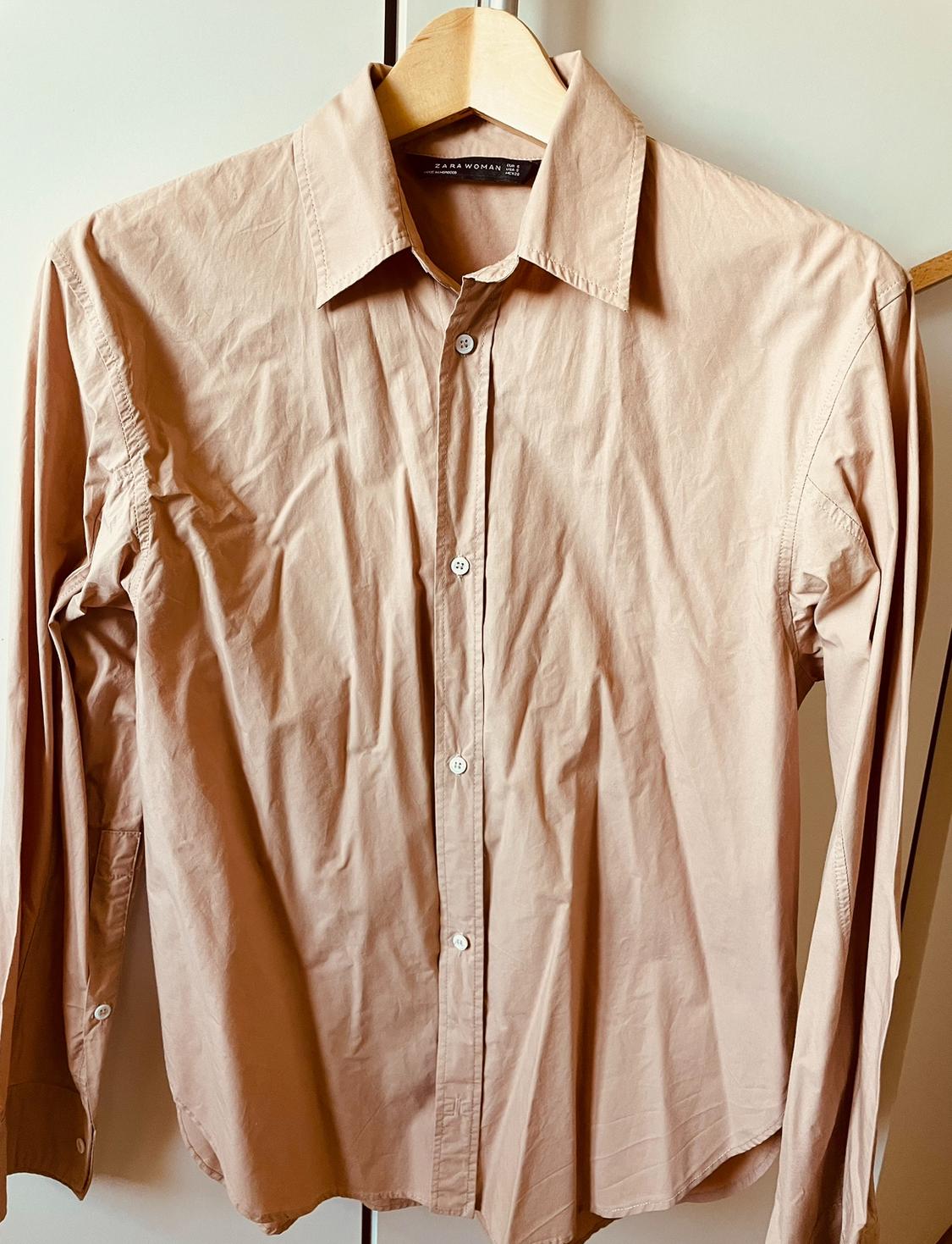 Front view of a beige shirt with a classic collar and white buttons.