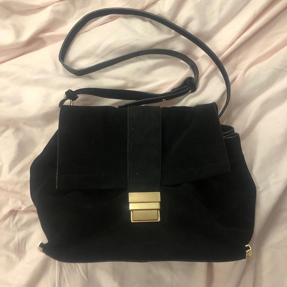 Front view of a black purse with a large flap and gold closure.